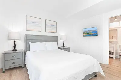 a white bedroom with a white bed and two night stands at 4Br Retreat One House From The Beach And Boardwalk By Beachview Rentals in Newport Beach