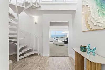 a living room with white walls and a staircase at Sea Glass Beach Road Villa On the SAND Luxury and relaxation in Dana Point