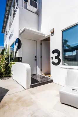 a white building with the number three on the door at Simple La Jolla Epic bungalow # 3 in San Diego