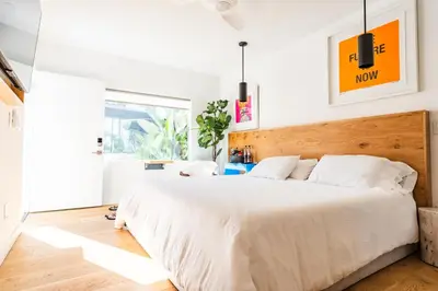 a bedroom with a large white bed with a wooden headboard at Simple La Jolla Epic bungalow # 2 in San Diego