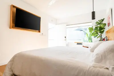 a bedroom with a white bed with a flat screen tv on the wall at Simple La Jolla Epic bungalow # 2 in San Diego