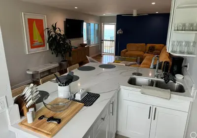 a kitchen with a counter with a sink and a living room at Amazing La Jolla Ocean View 2 bedroom apartment in San Diego