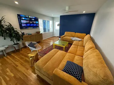 a living room with a large couch and a tv at Amazing La Jolla Ocean View 2 bedroom apartment in San Diego