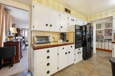 a kitchen with white cabinets and a refrigerator at Stay at Grandmas Entire Home with Yard & Balcony in San Diego