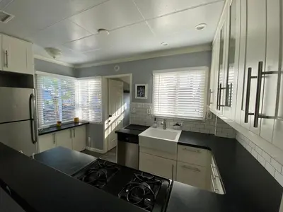 a kitchen with a stove and a sink and windows at Charming 1 Bedroom Home with Hot Tub & Bonus Room! in San Diego