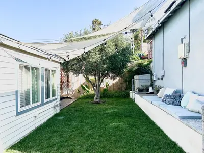 a backyard with green grass and a white house at Charming 1 Bedroom Home with Hot Tub & Bonus Room! in San Diego