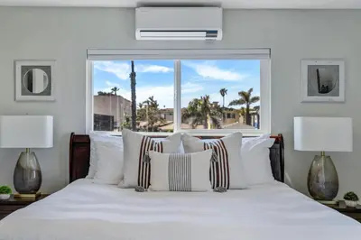 a bedroom with a white bed with a large window at Walk to Ocean Beach Stylish 2BR Apt with Patio in San Diego