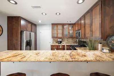 a kitchen with wooden cabinets and a large counter top at Surfing SapphirePrivate Rooftop Hot Tub wFirepit in San Diego
