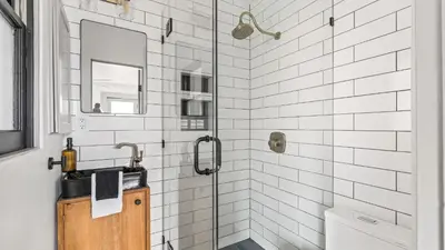 a bathroom with a shower with a sink and a mirror at 2 Side-by-Side San Diego Homes w Shared Backyard Firepit BBQ Casa Craftsman Casita on Landis by Avantstay in San Diego