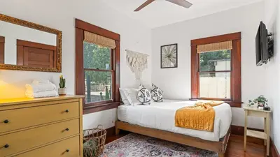 a bedroom with a bed and a dresser and windows at 2 Side-by-Side San Diego Homes w Shared Backyard Firepit BBQ Casa Craftsman Casita on Landis by Avantstay in San Diego