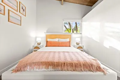 a white bedroom with a bed with an orange comforter at Spacious 4BR Retreat with Hot Tub Fire Pit and Patio in San Diego