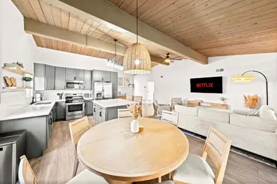 a kitchen and living room with a wooden table and chairs at Spacious 4BR Retreat with Hot Tub Fire Pit and Patio in San Diego