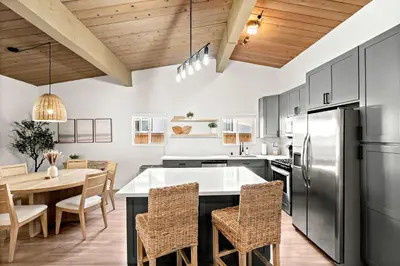 a kitchen with a table and a stainless steel refrigerator at Spacious 4BR Retreat with Hot Tub Fire Pit and Patio in San Diego