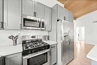 a kitchen with a stove and a stainless steel refrigerator at Spacious 4BR Retreat with Hot Tub Fire Pit and Patio in San Diego