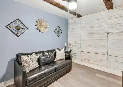 a leather couch in a living room with a wooden wall at Spacious Family Getaway with Grill Firepit and Patio in San Diego