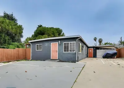 a small grey garage with a door and a fence at Spacious Family Getaway with Grill Firepit and Patio in San Diego