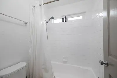 a white bathroom with a shower and a toilet at Steps to beach Best Location Villa in San Diego