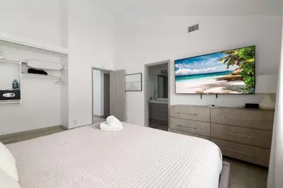 a bedroom with a white bed and a flat screen tv at Steps to beach Best Location Villa in San Diego
