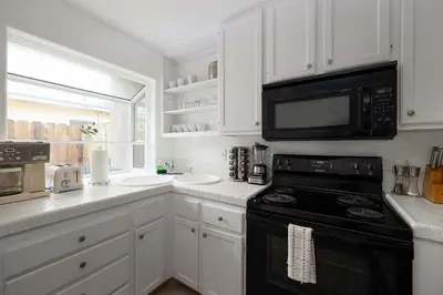 a kitchen with white cabinets and a black microwave at Steps to beach Best Location Villa in San Diego