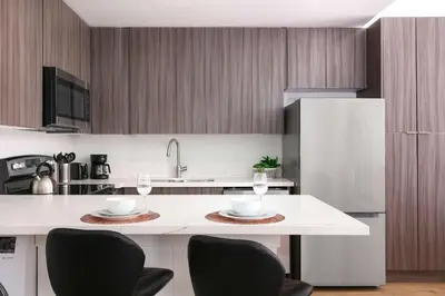 a kitchen with a white counter with chairs and a refrigerator at Bright 2BR Loft Sleeps 7 with Full Kitchen and Fast WiFi in San Diego