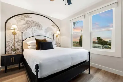 a bedroom with a large bed and two windows at Updated Historic Suite with Queen Bed and Kitchen in San Diego