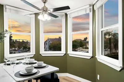a dining room with a table and three windows at Updated Historic Suite with Queen Bed and Kitchen in San Diego