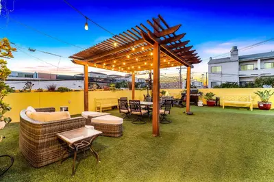 a wooden pergola with chairs and tables on a patio at Historic Apartment with Roof Deck in the Heart of North Park in San Diego