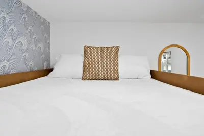 a bed with white sheets and a pillow on it at Spacious Group Getaway Games BBQ with Free Parking in San Diego