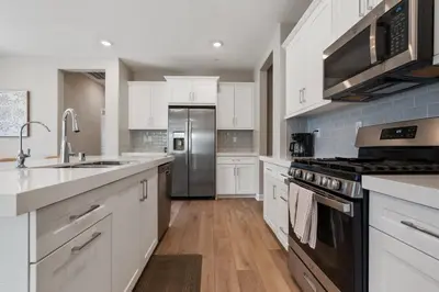 a kitchen with white cabinets and a stainless steel refrigerator at Family home with Private Gym in Escondido