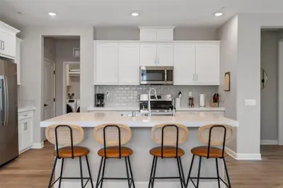 a kitchen with white cabinets and a island with four bar stools at Family home with Private Gym in Escondido