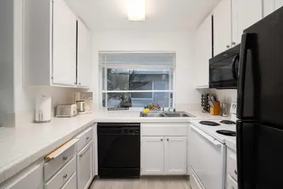 a kitchen with white cabinets and a black refrigerator at Walk to beach Great location Villa in San Diego