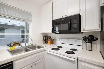 a white kitchen with a sink and a microwave at Walk to beach Great location Villa in San Diego