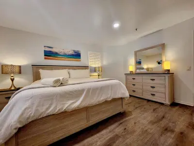 a bedroom with a large bed with a dresser and a mirror at Modern Coastal Escape Breathtaking Ocean in Imperial Beach