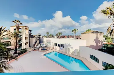 a swimming pool in front of a white building with palm trees at Modern Coastal Escape Breathtaking Ocean in Imperial Beach
