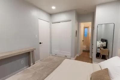 a white bedroom with a bed and a mirror at Relaxing Retreat in North Park in San Diego