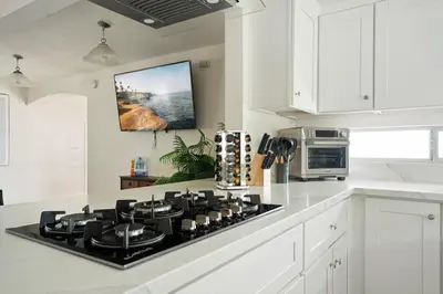 a kitchen with a stove top in a white kitchen at Near Safari & Beach - Backyard Games - AC - Pet OK in Escondido