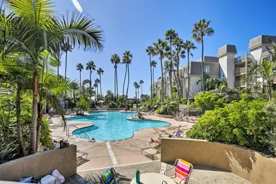 a swimming pool with palm trees and lawn chairs at Steps to Shore Condo with Resort Perks in Oceanside in Oceanside