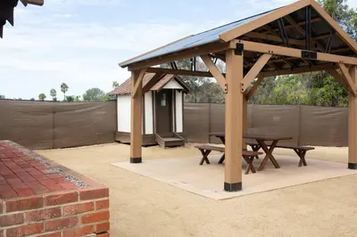 a wooden pavilion with a picnic table and a fence at The Vintage La Mesa Tudor in La Mesa