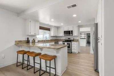 a kitchen with white cabinets and a island with bar stools at Hilltop Getaway with Sunset Views in Temecula