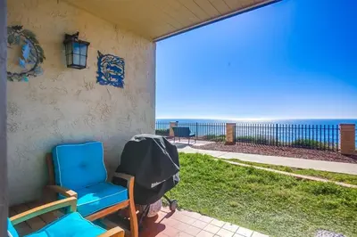 a porch with a blue chair and a view of the ocean at Ocean 11 condo in Solana Beach