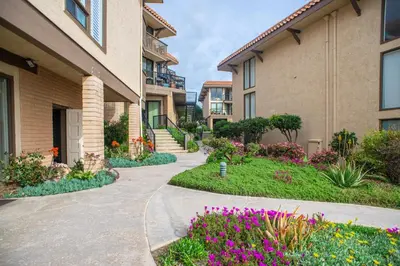 a walkway in front of a building with flowers at Ocean 11 condo in Solana Beach