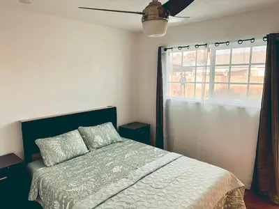 a bedroom with a bed with a ceiling fan and a window at Modern SD Oasis with Pool & HotTub in San Diego