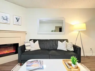a living room with a black couch and a fireplace at Prime Location and Stylish Apartment La Jolla UTC - Gym, Pool, Jacuzzi and Parking Access in San Diego