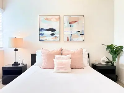a bedroom with a white bed with three paintings on the wall at Prime Location and Stylish Apartment La Jolla UTC - Gym, Pool, Jacuzzi and Parking Access in San Diego
