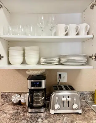 a kitchen counter with a coffee maker and plates at Prime Location and Stylish Apartment La Jolla UTC - Gym, Pool, Jacuzzi and Parking Access in San Diego