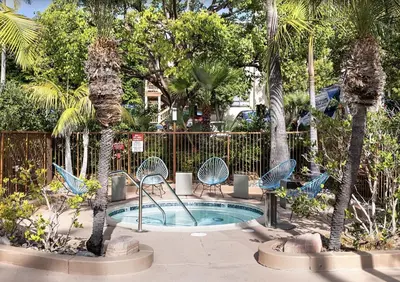 a patio with chairs and a pool with palm trees at Prime Location and Stylish Apartment La Jolla UTC - Gym, Pool, Jacuzzi and Parking Access in San Diego