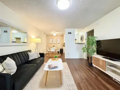 a living room with a black couch and a tv at Prime Location and Stylish Apartment La Jolla UTC - Gym, Pool, Jacuzzi and Parking Access in San Diego