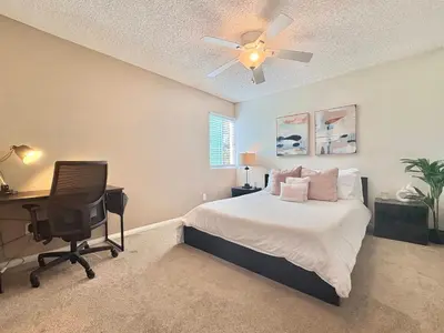 a bedroom with a bed and a desk and a ceiling fan at Prime Location and Stylish Apartment La Jolla UTC - Gym, Pool, Jacuzzi and Parking Access in San Diego