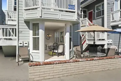 a house with a porch with chairs and an umbrella at 6Br Oceanview Getaway Steps From 27Th St Beach By Beachview Rentals in Newport Beach