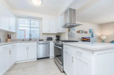 a kitchen with white cabinets and a stove top oven at 7Br Retreat, Oceanview Balcony And Patio, Steps From Sand By Beachview Rentals in Newport Beach